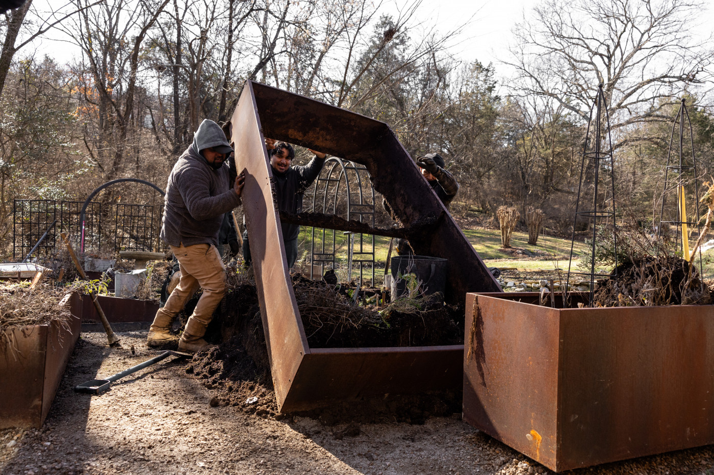 Men lifting a steel raised bed off of the ground