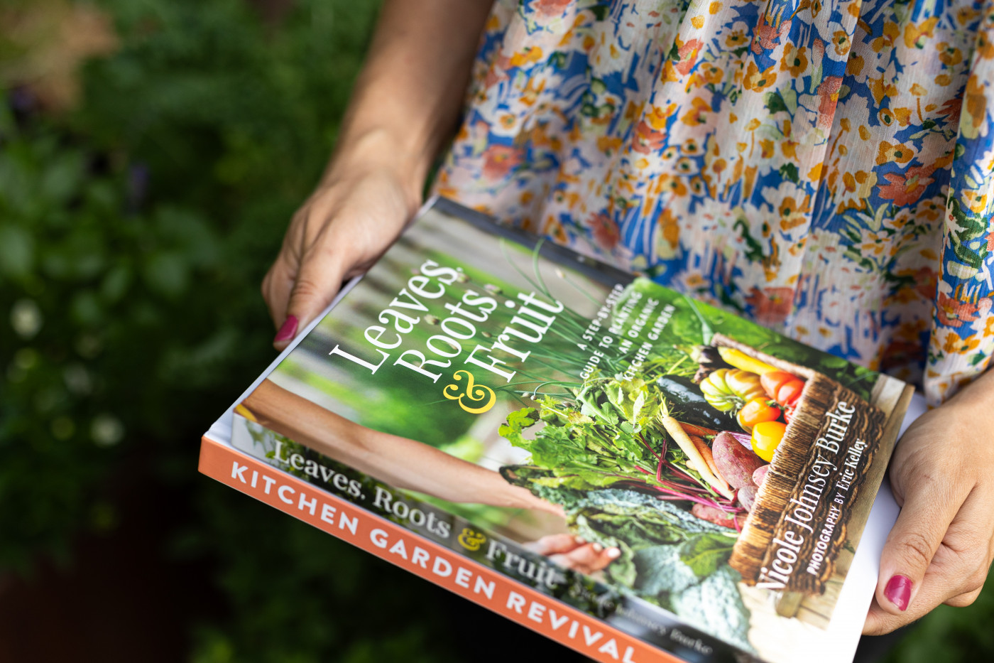 Hands holding a book titled Leaves, Roots and Fruit.