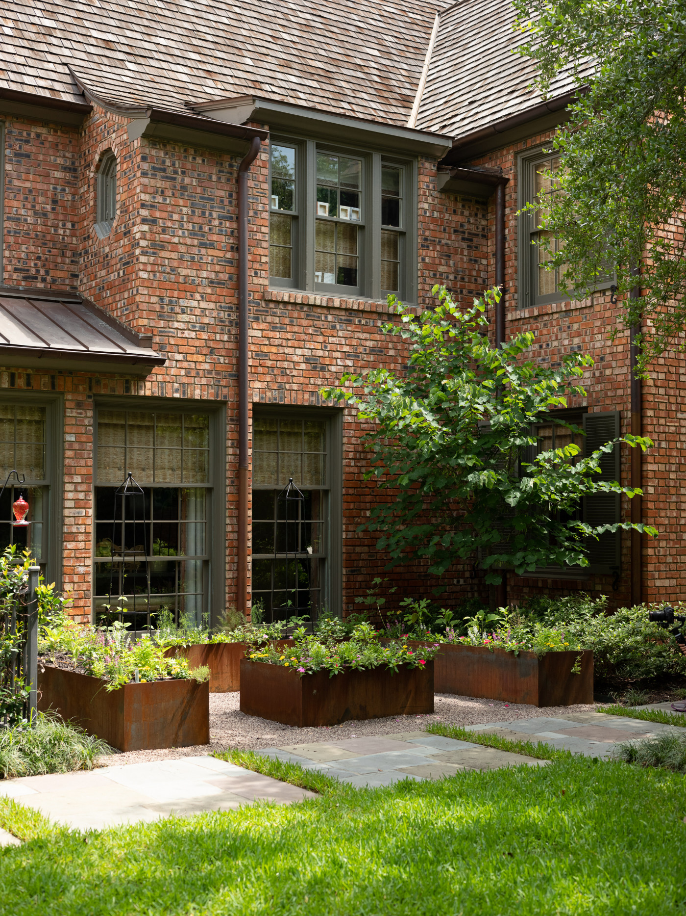 keyhole garden with corten steel raised beds nestled outside brick home