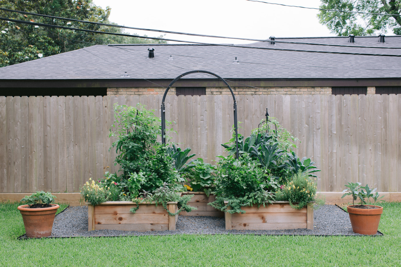 keyhole garden with cedar raised beds and arched trellis