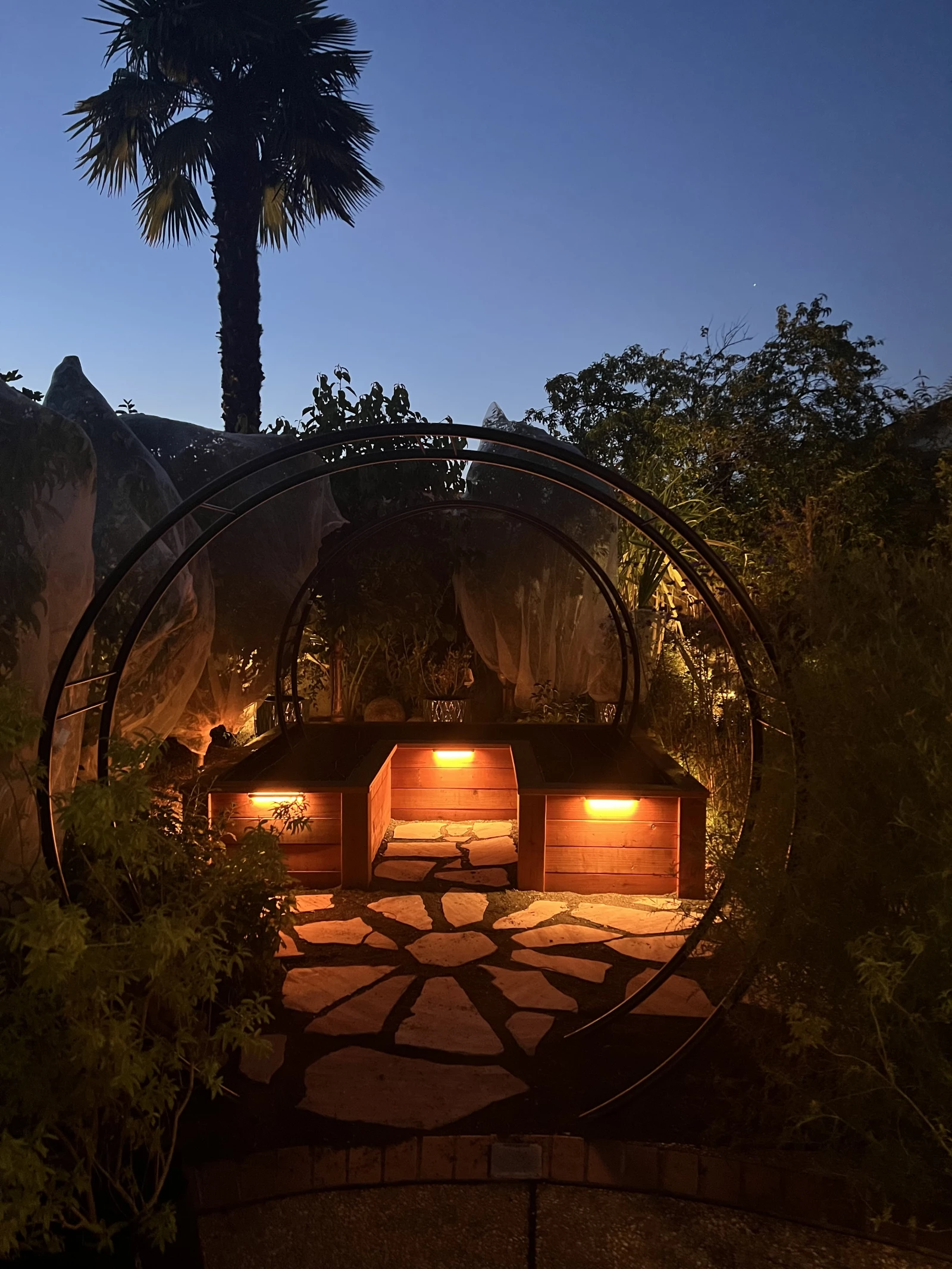 a garden lit up at night by lights attached to the side of the beds