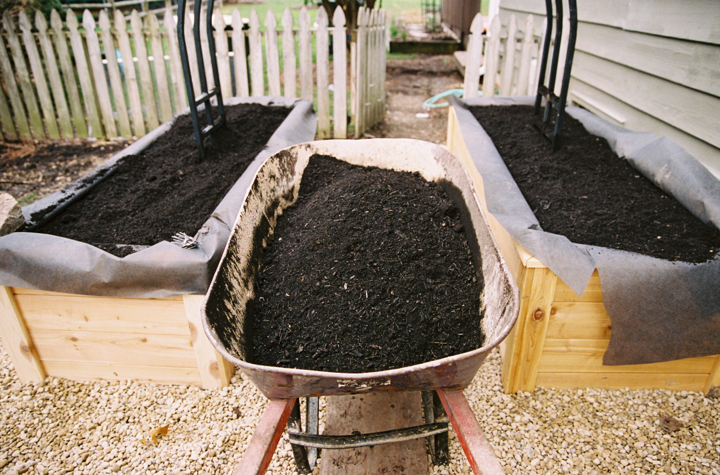 A wheelbarrow and two raised beds with soil