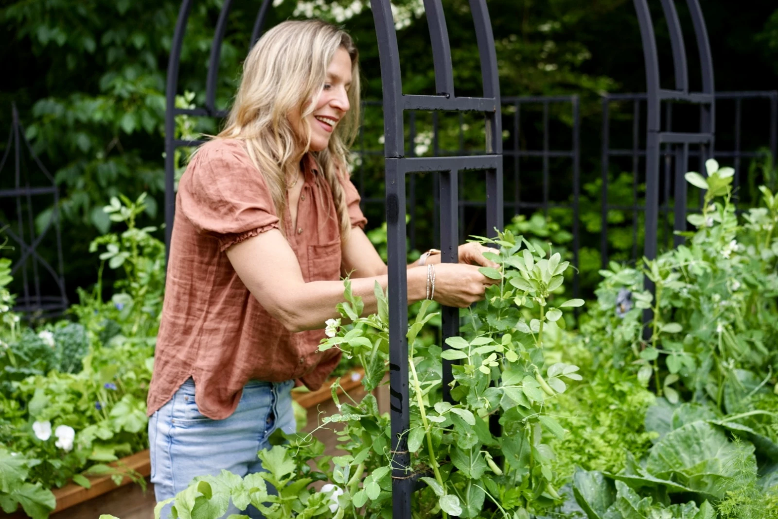 Nicole tying a plant to an arch trellis